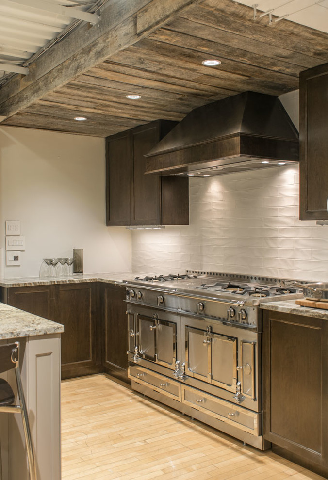 Example of a mid-sized transitional l-shaped light wood floor and beige floor enclosed kitchen design in Boston with dark wood cabinets, granite countertops, white backsplash, subway tile backsplash, stainless steel appliances, recessed-panel cabinets and a peninsula
