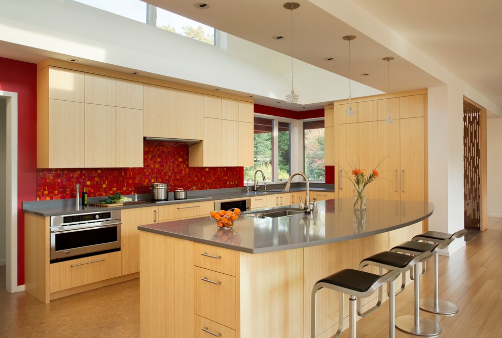 Inspiration for a large contemporary kitchen in Boston with flat-panel cabinets, light wood cabinets, red splashback, ceramic splashback, stainless steel appliances, light hardwood floors, with island and an undermount sink.