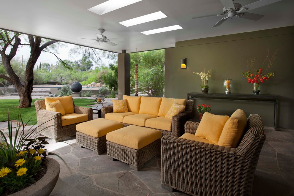 This is an example of a contemporary patio in Phoenix with natural stone pavers and a roof extension.