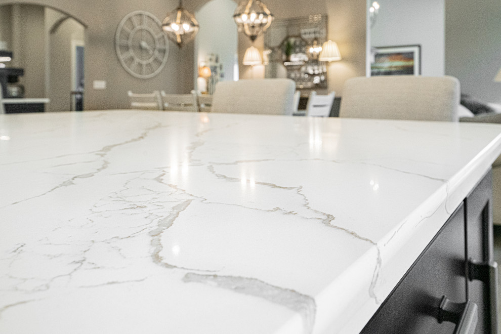 Example of a large transitional u-shaped medium tone wood floor, gray floor and tray ceiling open concept kitchen design with an undermount sink, shaker cabinets, white cabinets, quartzite countertops, multicolored backsplash, porcelain backsplash, stainless steel appliances, an island and white countertops
