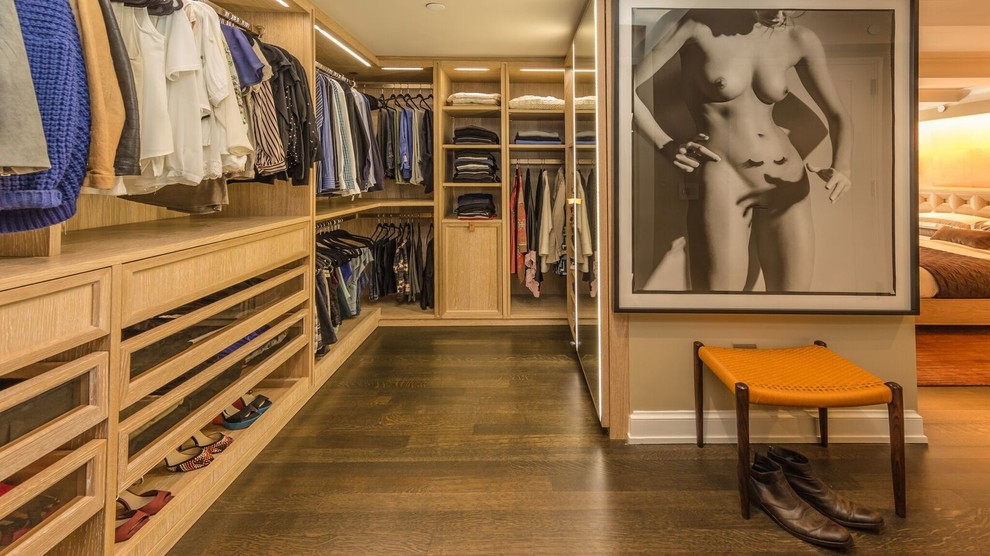 Mid-sized contemporary gender-neutral walk-in wardrobe in New York with raised-panel cabinets, light wood cabinets and dark hardwood floors.