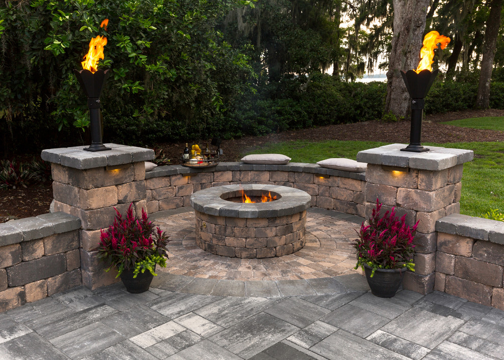 This is an example of an expansive traditional backyard patio in Jacksonville with a fire feature, natural stone pavers and no cover.