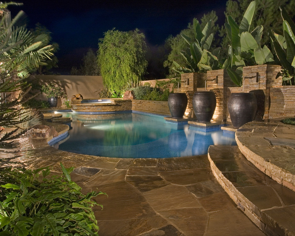 This is an example of a mediterranean backyard custom-shaped pool in Orange County with a water feature.
