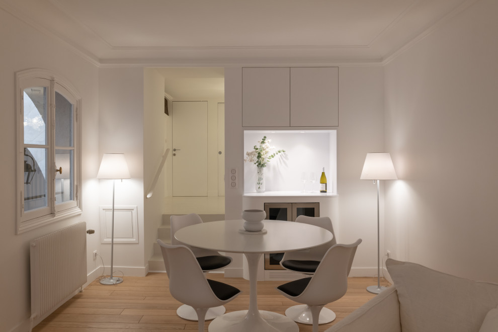 Exemple d'une salle à manger ouverte sur le salon tendance de taille moyenne avec un mur blanc, parquet clair, aucune cheminée, un sol marron et éclairage.