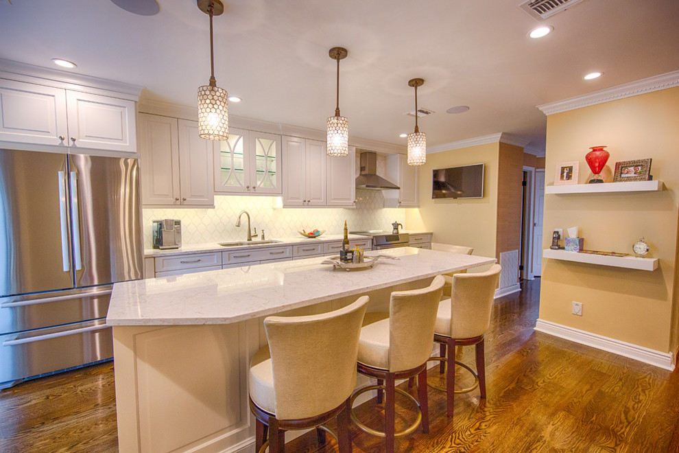Inspiration for a mid-sized transitional single-wall dark wood floor and brown floor eat-in kitchen remodel in New York with an undermount sink, raised-panel cabinets, white cabinets, quartz countertops, white backsplash, glass tile backsplash, stainless steel appliances and an island