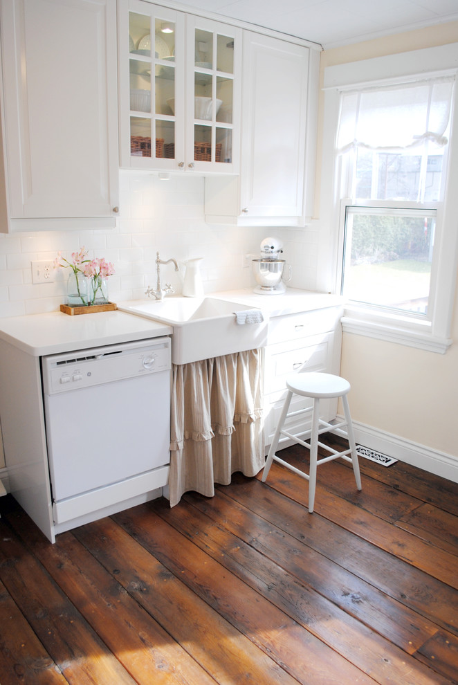 Photo of a traditional kitchen in Other with a farmhouse sink, glass-front cabinets, white cabinets, white splashback, subway tile splashback and white appliances.