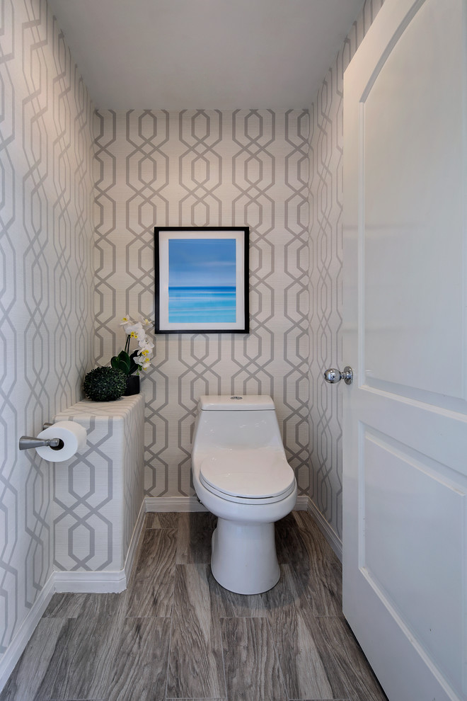 Design ideas for a mid-sized contemporary powder room in Orange County with flat-panel cabinets, medium wood cabinets, a one-piece toilet, porcelain tile, grey walls, medium hardwood floors, an undermount sink, marble benchtops and grey floor.