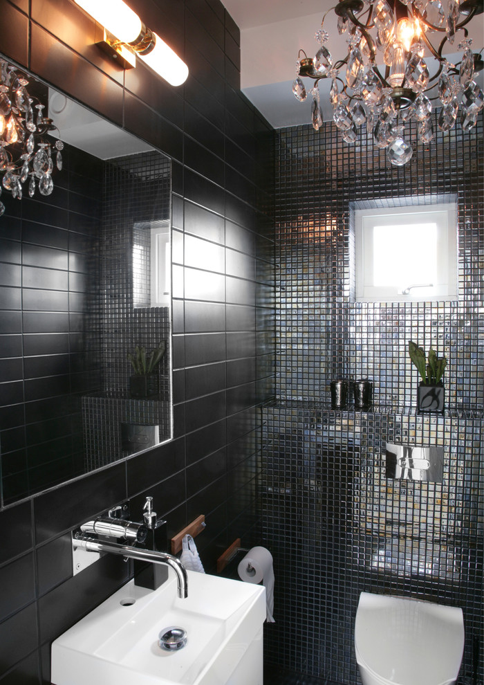 This is an example of a small contemporary powder room in Gothenburg with a wall-mount toilet, black tile and black walls.