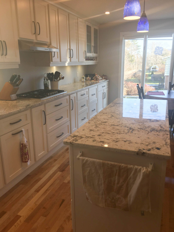 Eat-in kitchen - mid-sized transitional u-shaped medium tone wood floor and brown floor eat-in kitchen idea with recessed-panel cabinets, white cabinets, granite countertops, stainless steel appliances, an island and multicolored countertops