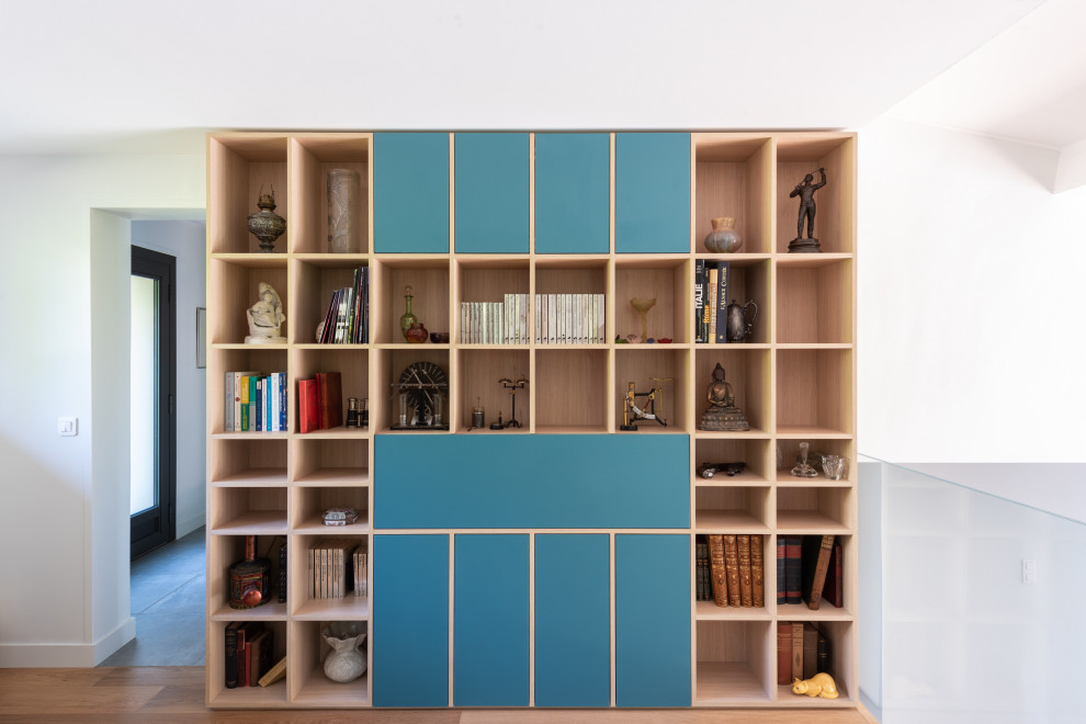 Esempio di uno studio nordico di medie dimensioni con libreria, pareti blu, parquet chiaro e scrivania incassata