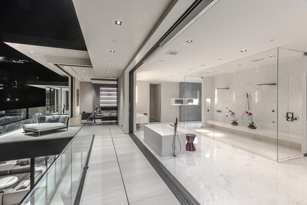 This is an example of a contemporary master bathroom in Los Angeles with a freestanding tub, a double shower, white tile, white floor, a hinged shower door, marble and marble floors.