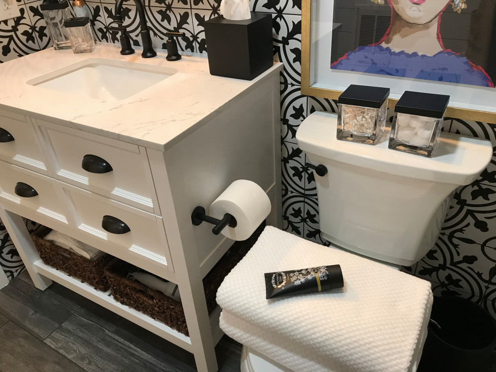 Inspiration for a mid-sized traditional master bathroom in Philadelphia with shaker cabinets, white cabinets, an alcove tub, a shower/bathtub combo, a two-piece toilet, black and white tile, cement tile, white walls, ceramic floors, an undermount sink, quartzite benchtops, multi-coloured floor, a sliding shower screen, white benchtops, a niche, a single vanity, a freestanding vanity and planked wall panelling.