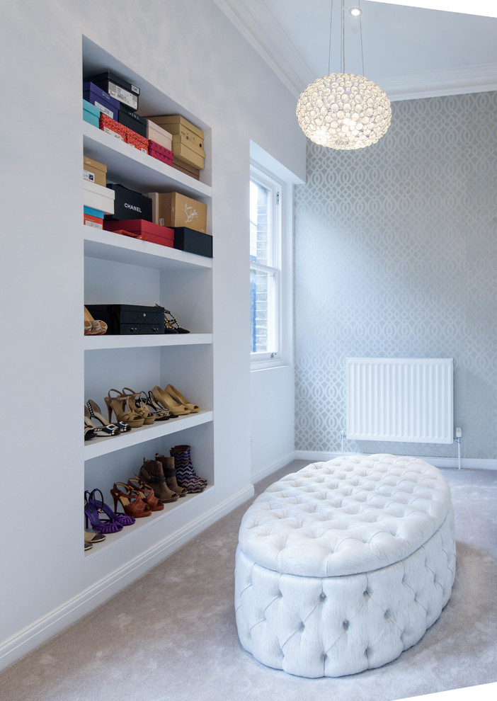 Photo of a mid-sized transitional women's walk-in wardrobe in London with open cabinets, carpet and grey floor.