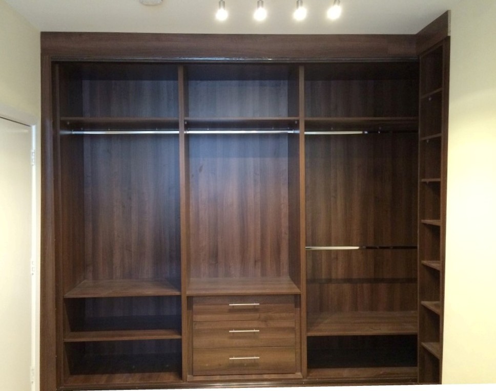 Inspiration for a mid-sized contemporary gender-neutral built-in wardrobe in London with glass-front cabinets, dark wood cabinets and light hardwood floors.