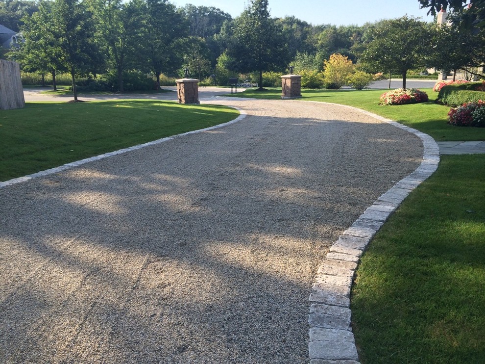 Photo of a large traditional front yard partial sun driveway in Chicago with natural stone pavers.