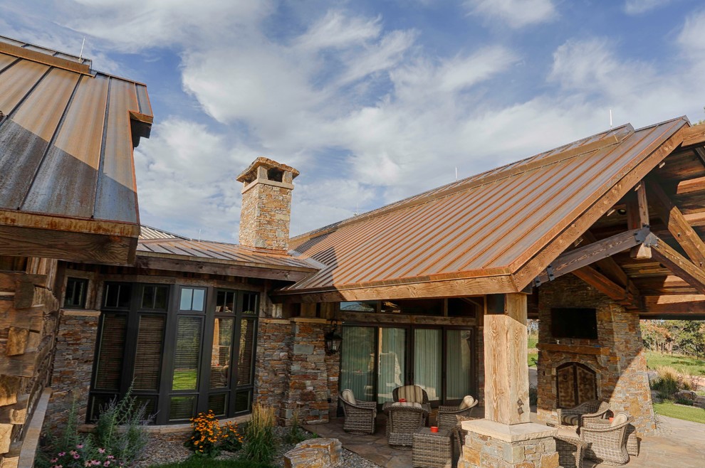 Photo of a country brown house exterior in Other with stone veneer and a metal roof.