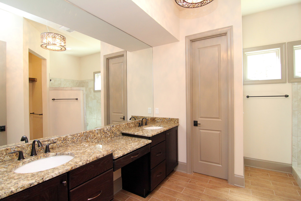 Photo of a mid-sized contemporary master bathroom in Raleigh with an undermount sink, recessed-panel cabinets, dark wood cabinets, granite benchtops, a corner shower, a one-piece toilet, brown tile, ceramic tile, beige walls and ceramic floors.