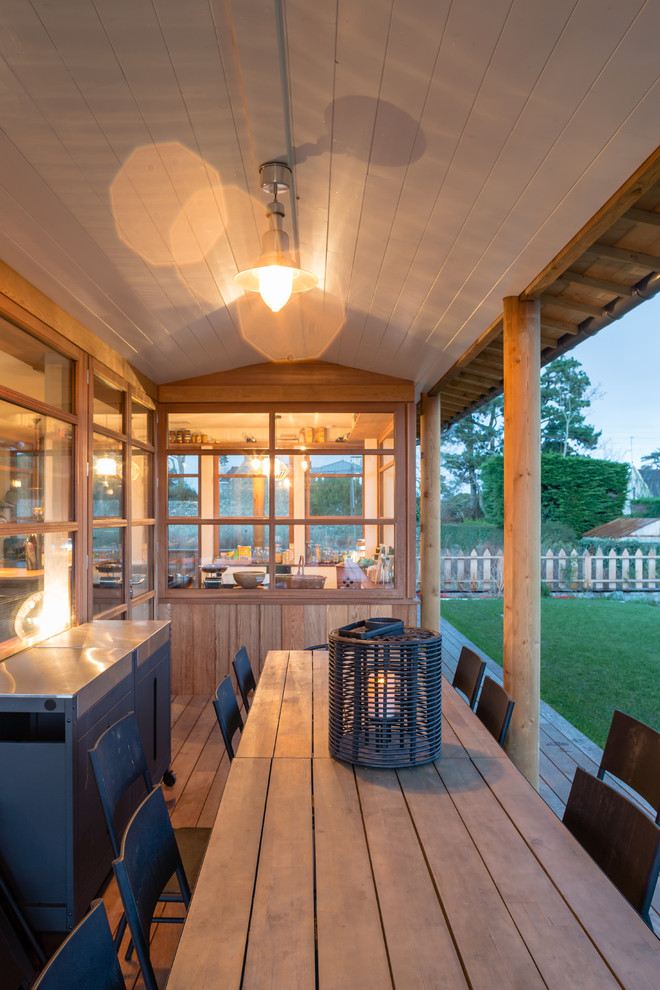 This is an example of a mid-sized country backyard deck in Rennes with an outdoor kitchen and a roof extension.