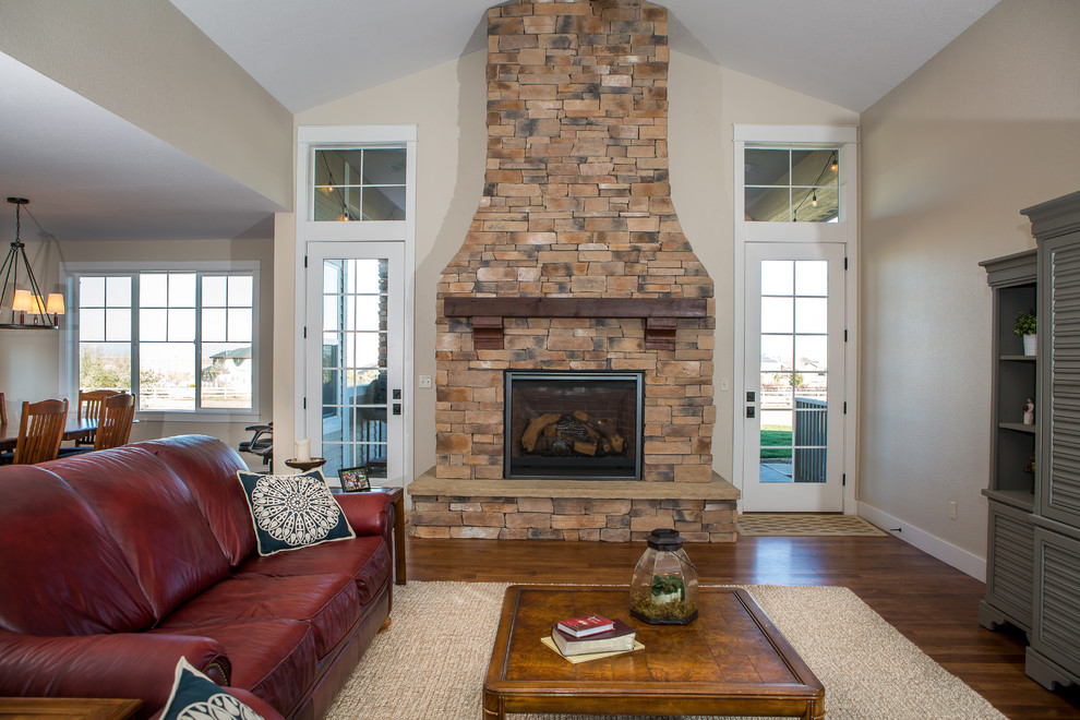 Photo of a large arts and crafts open concept living room in Denver with beige walls, medium hardwood floors, a standard fireplace, a stone fireplace surround and brown floor.