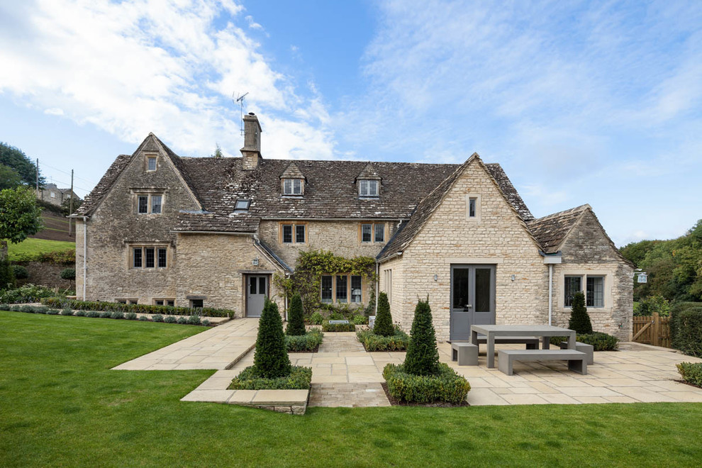 Three-storey beige house exterior in Gloucestershire with stone veneer and a gable roof.