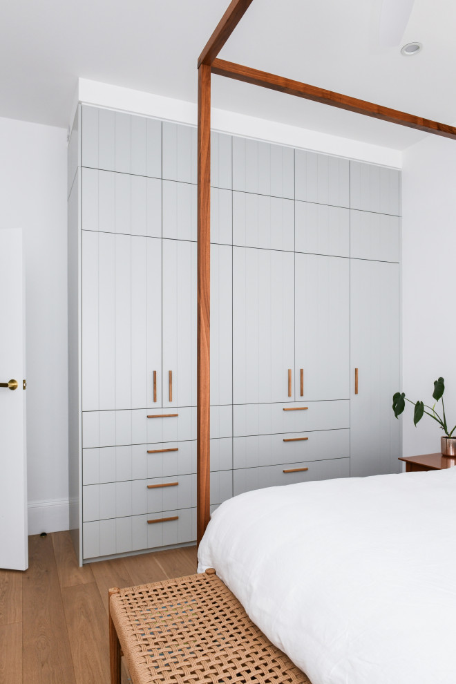 На фото: встроенный шкаф среднего размера, унисекс в морском стиле с серыми фасадами и коричневым полом