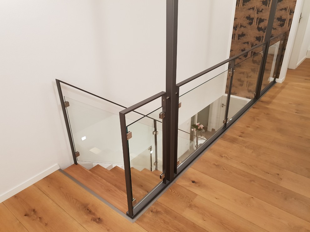 This is an example of a mid-sized contemporary wood straight staircase in Other with wood risers and glass railing.