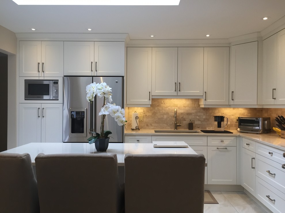 Large transitional l-shaped ceramic tile and beige floor kitchen photo in Toronto with an undermount sink, shaker cabinets, white cabinets, beige backsplash, subway tile backsplash, stainless steel appliances and an island