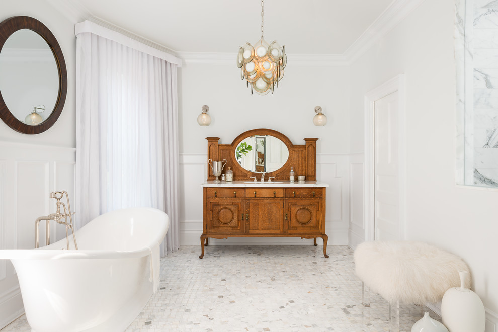 This is an example of a mid-sized traditional master bathroom in Toronto with marble benchtops, a freestanding tub, white walls, medium wood cabinets, marble floors, white floor and recessed-panel cabinets.