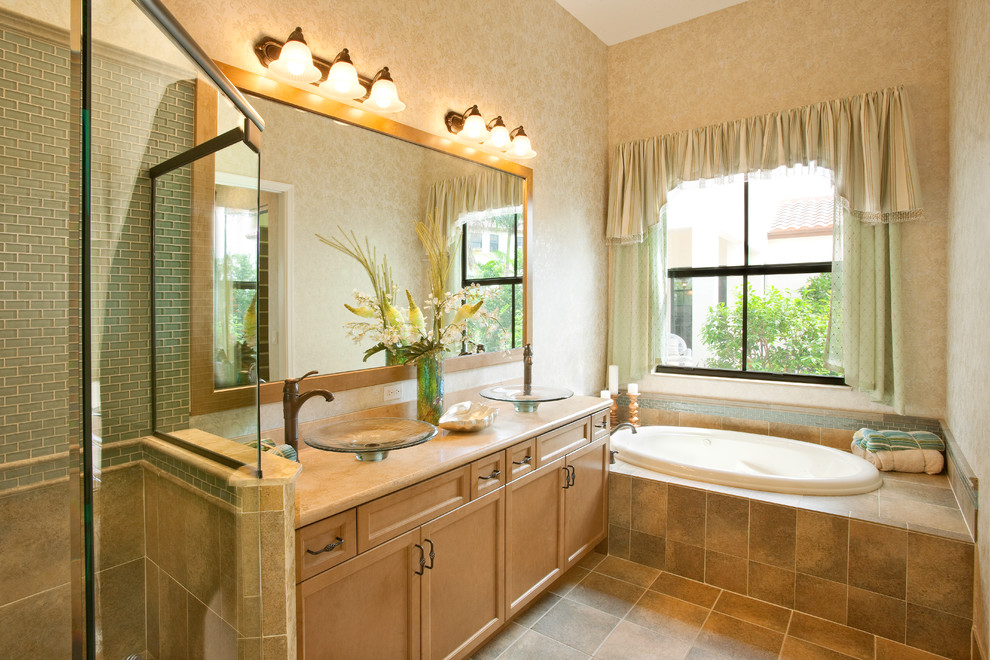 Transitional master bathroom in Miami with a vessel sink, recessed-panel cabinets, light wood cabinets, granite benchtops, a drop-in tub, a corner shower, glass tile, beige walls and ceramic floors.