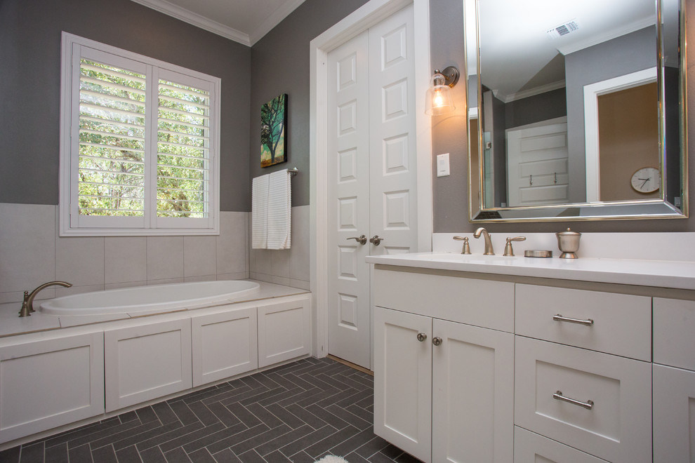 Inspiration for a mid-sized transitional master gray tile and ceramic tile ceramic tile and black floor drop-in bathtub remodel in Austin with shaker cabinets, white cabinets, a two-piece toilet, gray walls, an undermount sink, quartz countertops and a hinged shower door