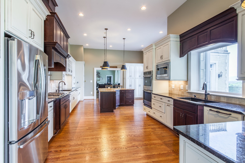 Eat-in kitchen - huge transitional medium tone wood floor eat-in kitchen idea in DC Metro with raised-panel cabinets, granite countertops, stainless steel appliances and an island