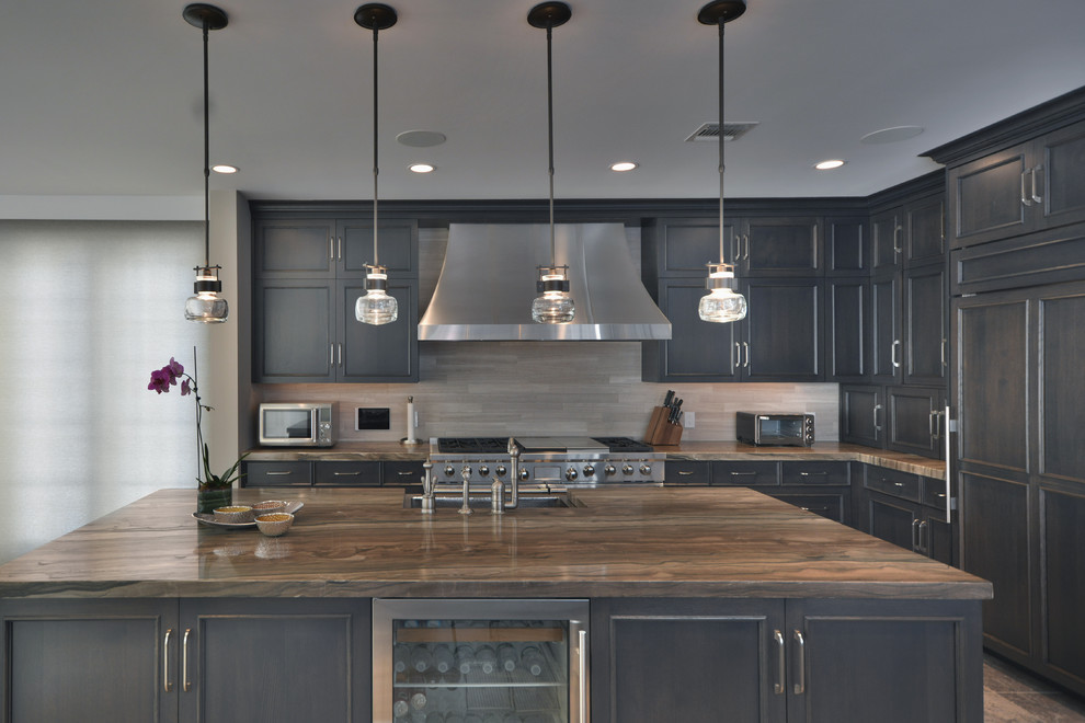 Example of a large transitional l-shaped travertine floor eat-in kitchen design in New York with a farmhouse sink, raised-panel cabinets, dark wood cabinets, quartzite countertops, gray backsplash, stainless steel appliances and two islands