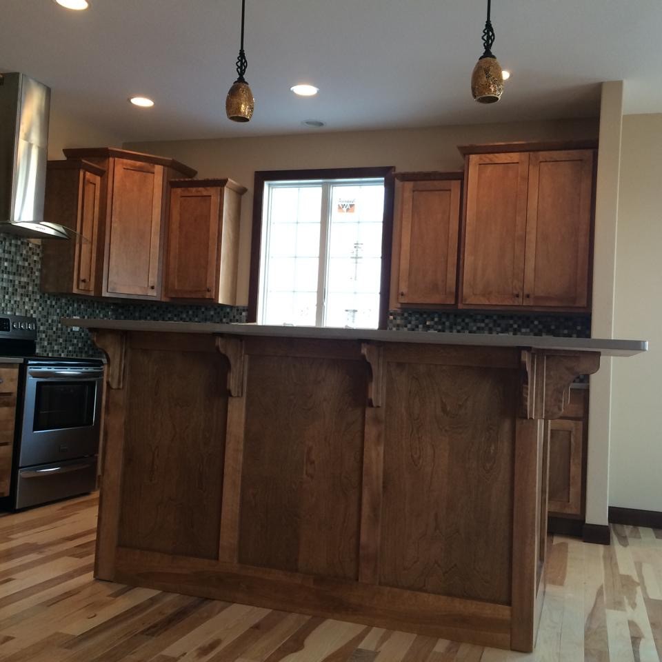 Mid-sized mountain style l-shaped light wood floor kitchen photo with shaker cabinets, medium tone wood cabinets, multicolored backsplash, mosaic tile backsplash, stainless steel appliances and an island