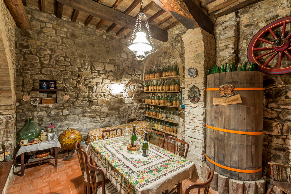 Photo of a small country wine cellar in Florence with terra-cotta floors, display racks and orange floor.