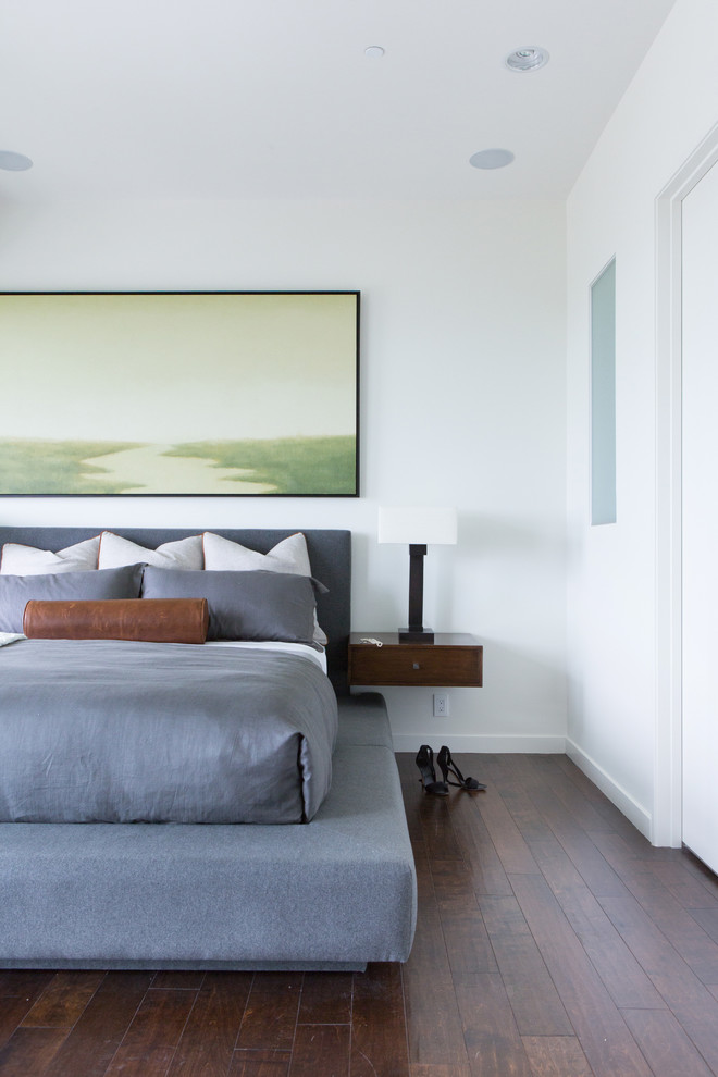 This is an example of a large transitional master bedroom in San Diego with white walls and dark hardwood floors.