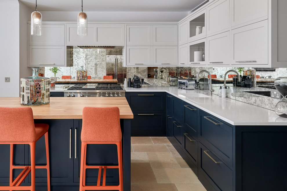 Design ideas for an expansive transitional galley open plan kitchen in Hampshire with a drop-in sink, recessed-panel cabinets, grey cabinets, granite benchtops, metallic splashback, mirror splashback, panelled appliances, ceramic floors, with island, beige floor and white benchtop.