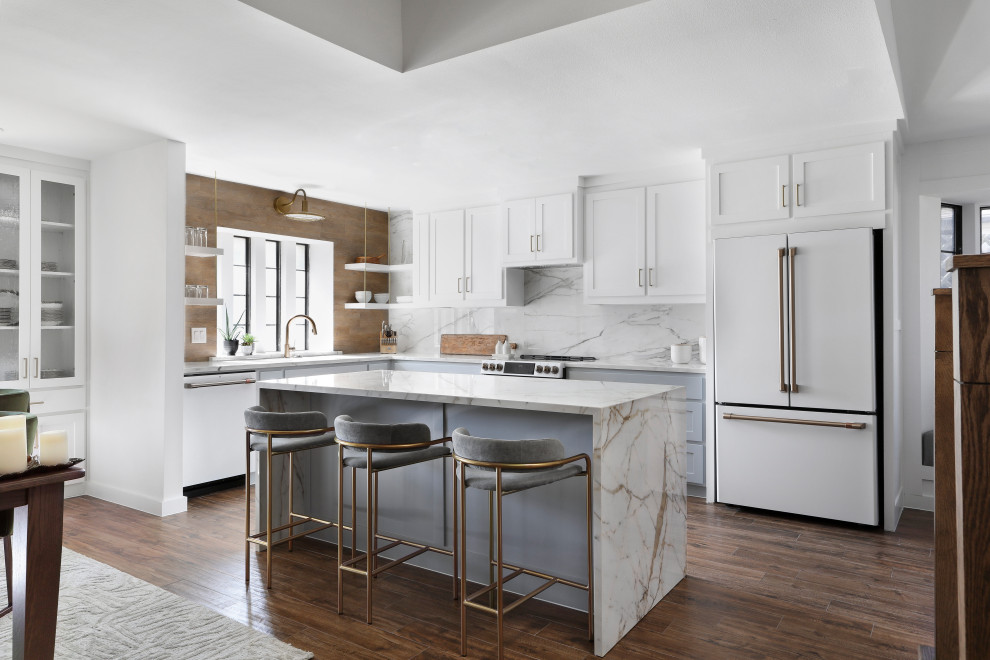 Photo of a transitional l-shaped kitchen in Dallas with an undermount sink, shaker cabinets, white cabinets, white splashback, white appliances, dark hardwood floors, with island, brown floor, white benchtop and vaulted.