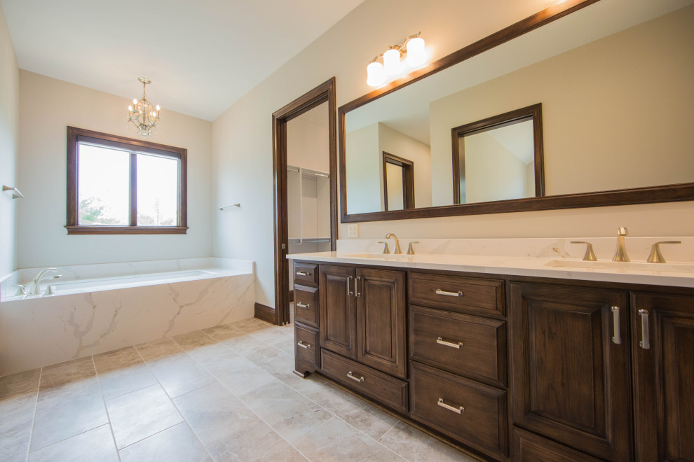 Photo of an expansive traditional ensuite bathroom in Indianapolis with raised-panel cabinets, brown cabinets, an alcove bath, a double shower, a bidet, beige walls, porcelain flooring, a submerged sink, marble worktops, brown floors, an open shower, multi-coloured worktops, a shower bench, double sinks and a freestanding vanity unit.