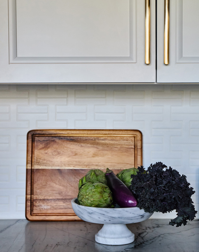 Example of a mid-sized transitional galley medium tone wood floor enclosed kitchen design in Chicago with a single-bowl sink, recessed-panel cabinets, white cabinets, quartzite countertops, white backsplash, ceramic backsplash, stainless steel appliances, an island and white countertops