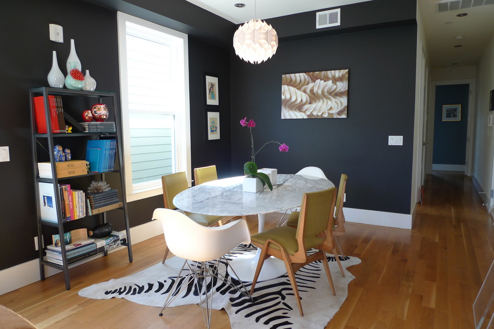 This is an example of a contemporary open plan dining in San Francisco with black walls and light hardwood floors.