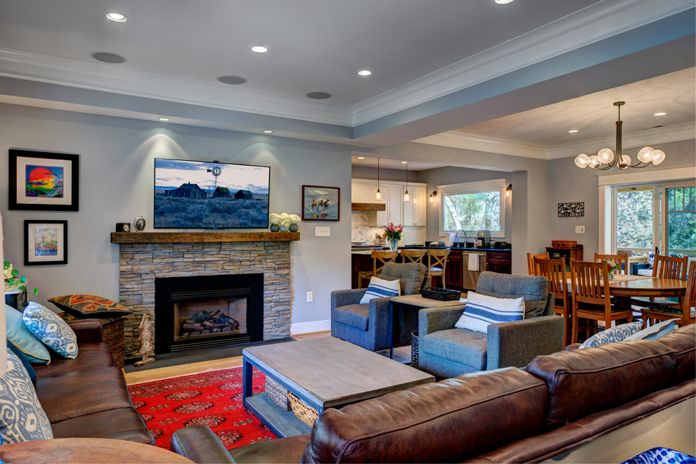 This is an example of a mid-sized contemporary open concept living room in DC Metro with a library, blue walls, light hardwood floors, a standard fireplace, a stone fireplace surround and a wall-mounted tv.