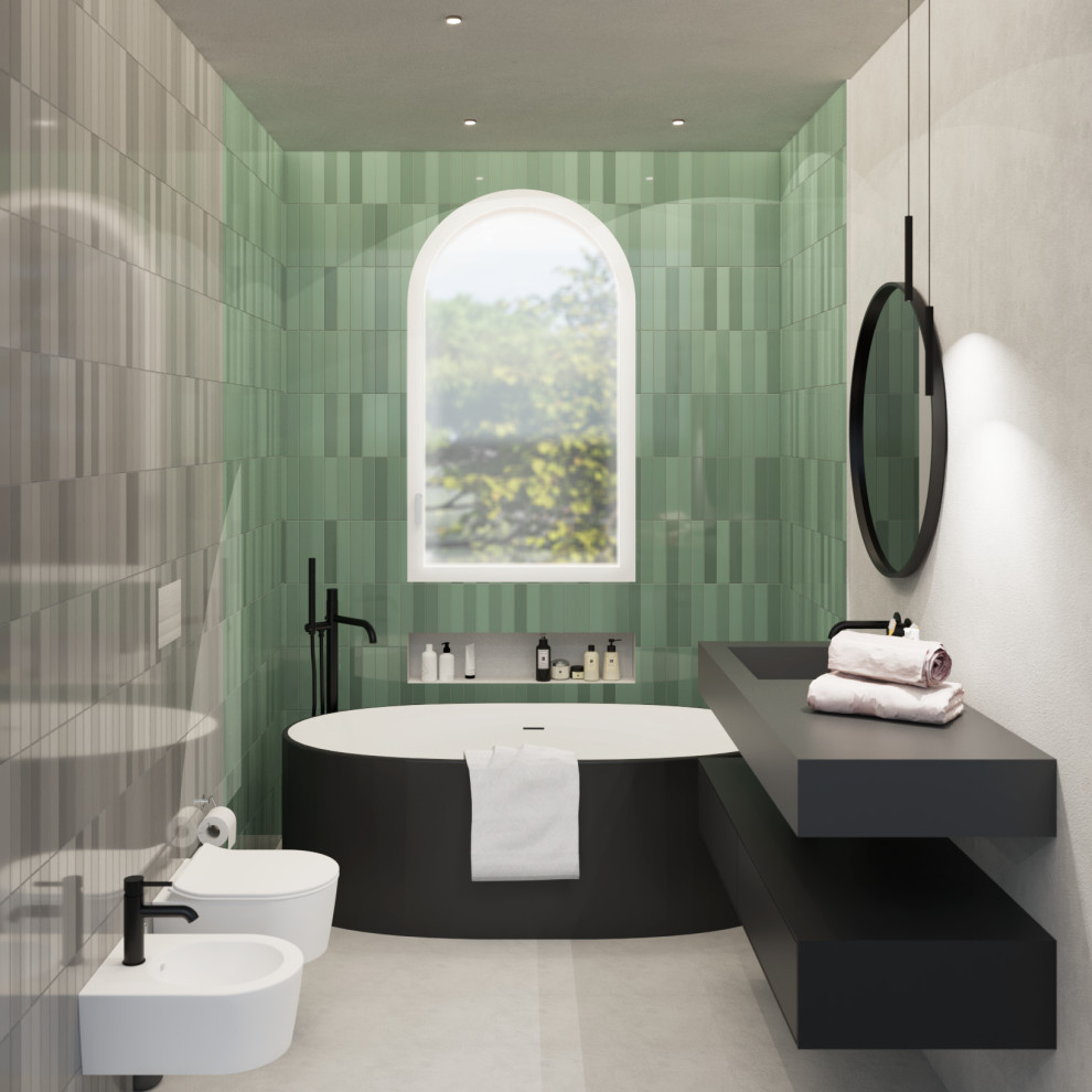 Foto på ett litet funkis grå badrum, med släta luckor, svarta skåp, ett fristående badkar, en toalettstol med separat cisternkåpa, grön kakel, stickkakel, flerfärgade väggar, betonggolv, ett integrerad handfat, bänkskiva i akrylsten och grått golv