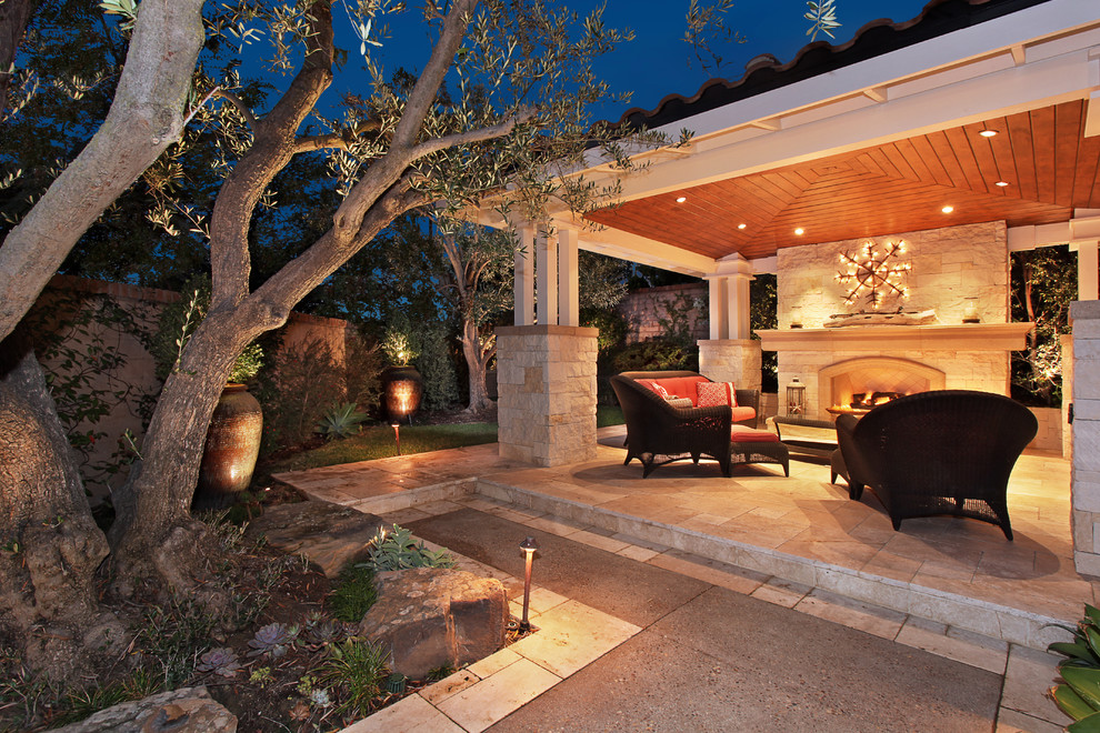 Mid-sized mediterranean backyard patio in Orange County with a fire feature, natural stone pavers and a roof extension.
