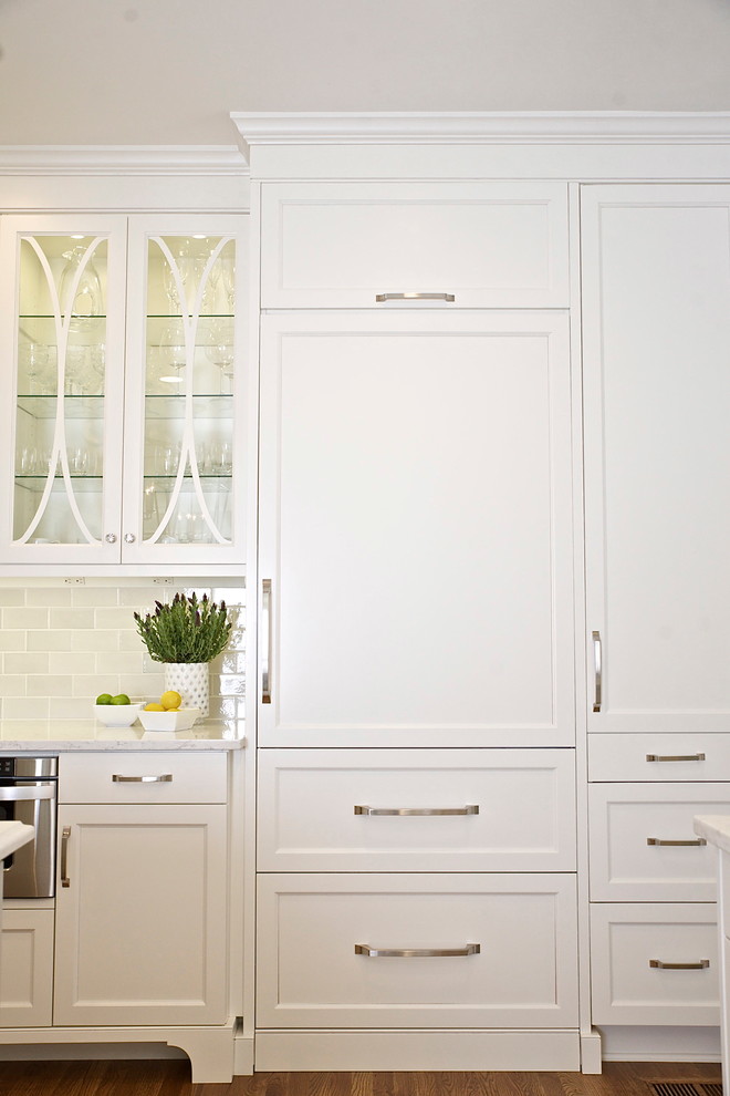 Inspiration for a large transitional medium tone wood floor kitchen remodel in Atlanta with an undermount sink, glass-front cabinets, white cabinets, quartz countertops, gray backsplash, subway tile backsplash, paneled appliances and an island