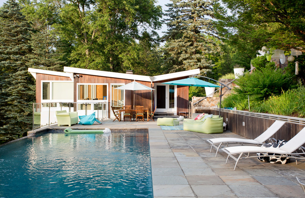 Design ideas for a midcentury backyard rectangular infinity pool in New York.