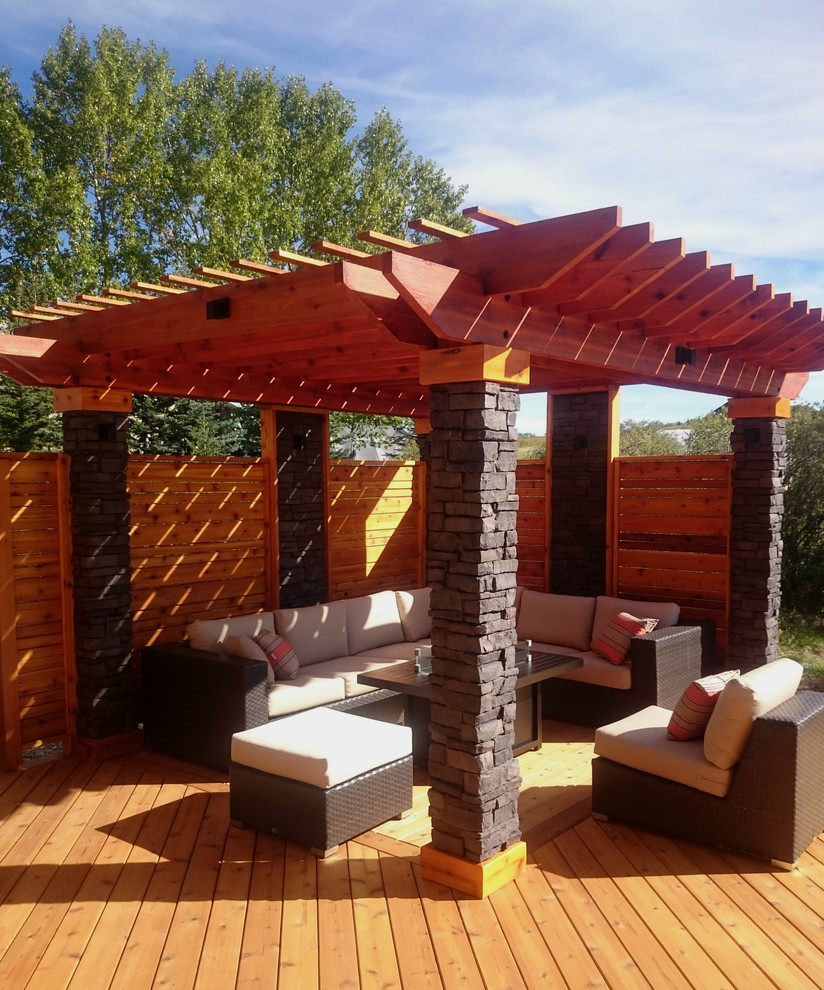 This is an example of a mid-sized modern backyard deck in Calgary with a fire feature and a pergola.