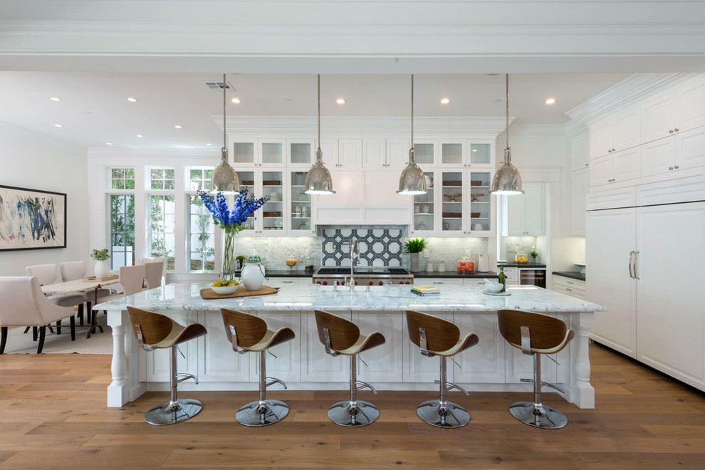 Design ideas for a transitional eat-in kitchen in Los Angeles with glass-front cabinets, white cabinets, multi-coloured splashback, stainless steel appliances, light hardwood floors and with island.