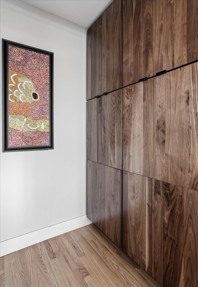 Imagen de armario unisex y abovedado retro pequeño con armarios con paneles lisos, puertas de armario de madera oscura, suelo de madera en tonos medios y suelo marrón