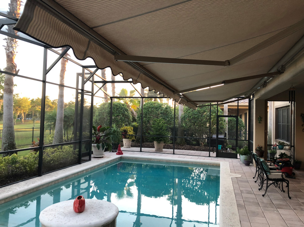 Design ideas for a large mediterranean backyard screened-in verandah in Orlando with an awning.