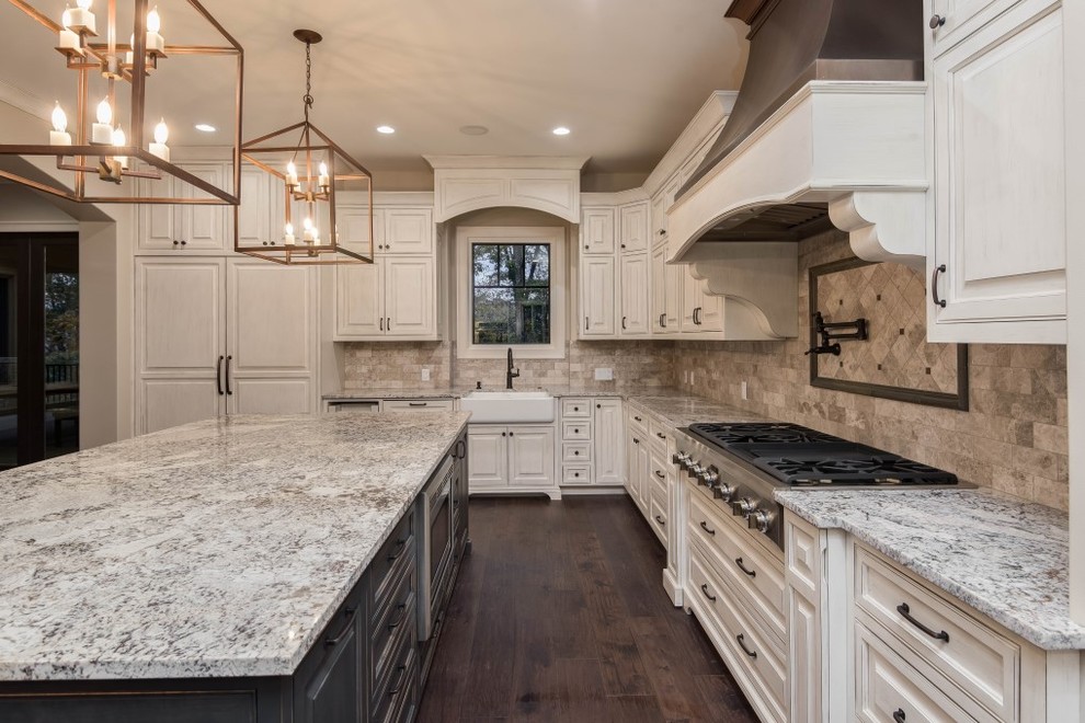 Inspiration for a large country l-shaped open plan kitchen in Other with a farmhouse sink, white cabinets, granite benchtops, beige splashback, stainless steel appliances, dark hardwood floors, with island and brown floor.